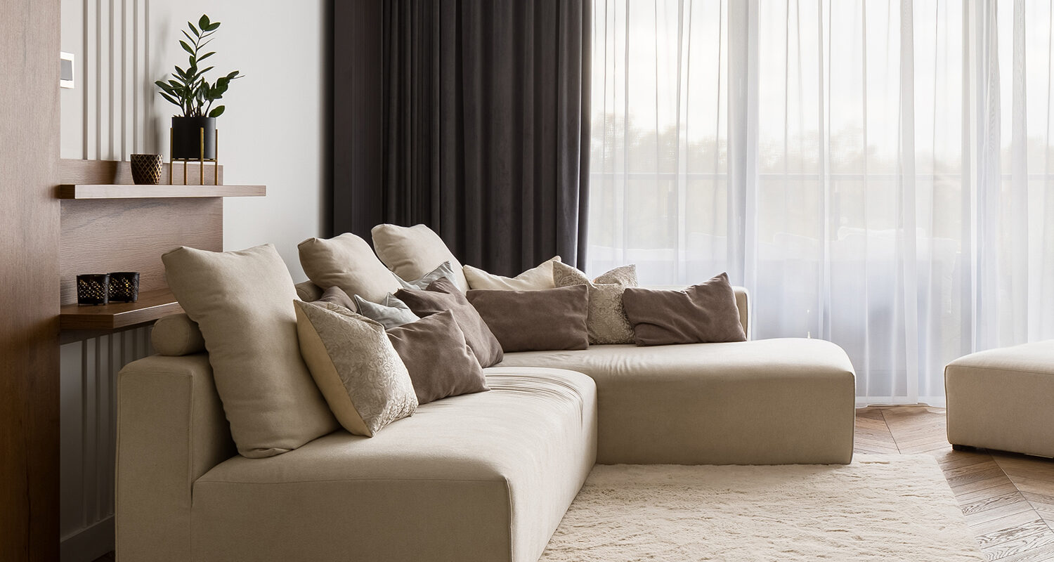 Luxury living room with big beige corner sofa and wooden floor and big windows, panorama
